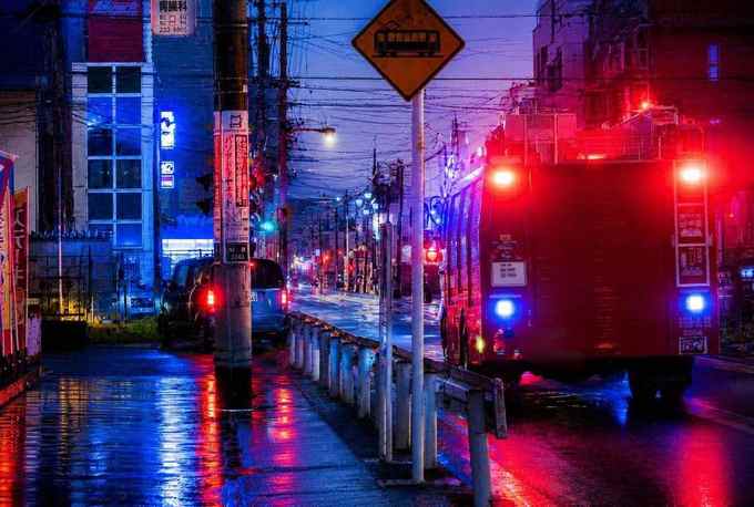 แสงสีแดงและน้ำเงินจากรถฉุกเฉินบนถนนญี่ปุ่นยามค่ำคืน